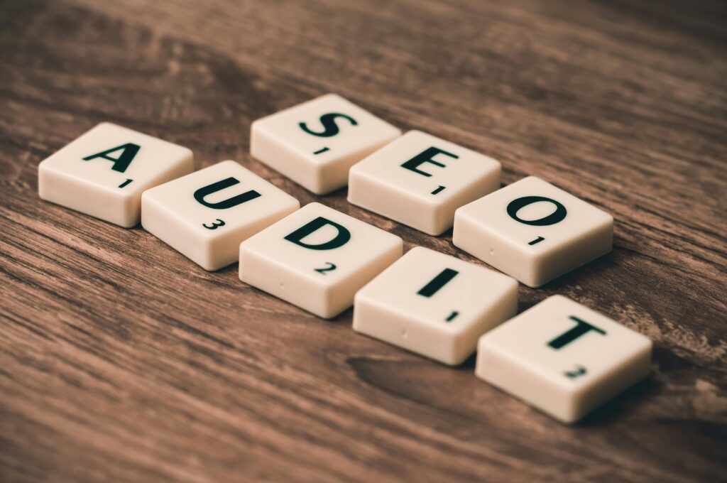 Scrabble tiles spelling SEO Audit on wooden surface, symbolizing digital marketing strategies.